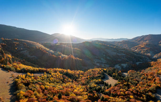 istock Sun rises above high mountain peaks with yellowed trees 1365895264
