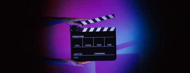 Hand holds empty film making clapperboard on color background in studio