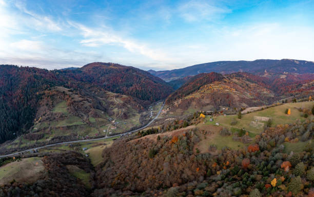 istock Ground road in high mountains with green forest at sunrise 1365896546