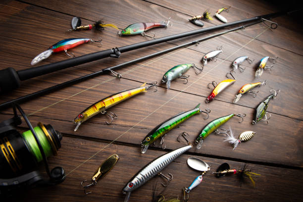 Fishing tackle - fishing spinning rod, hooks and lures on wooden background. Active hobby recreation concept. stock photo