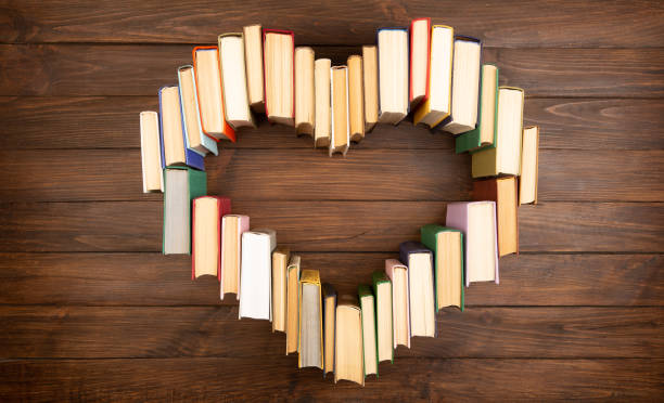 Love of books reading. Stack of books in the colored cover lay on the table in the shape of a heart. Library, education. Empty space for Your text. stock photo