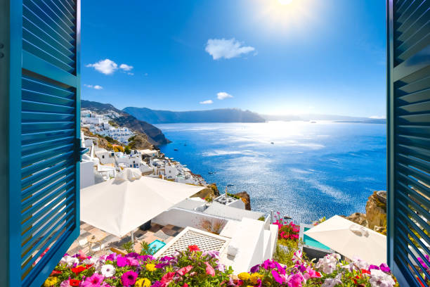 Santorini Window View with Flowers View from an open window with blue shutters of the Aegean sea, caldera, coastline and whitewashed town of Oia, Santorini, Greece. looking through window stock pictures, royalty-free photos & images