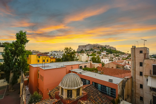 Sunset view of the ancient Parthenon and Acropolis Hill through an open window overlooking the Plaka district of Athens, Greece.