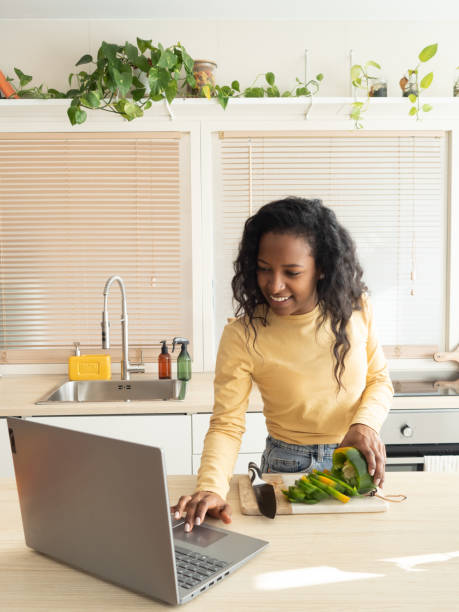 istock Latin American woman in the kitchen at home cooking while watching a tutorial 1365899159