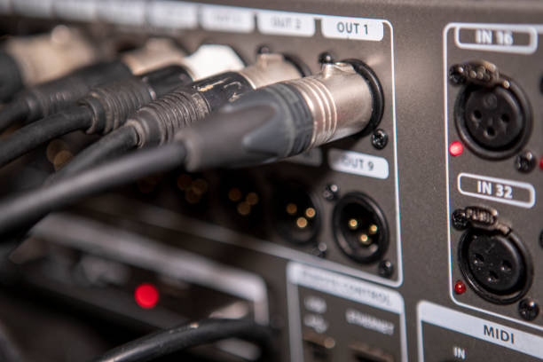 Instrument audio jack connectors inserted into channels on a mixing desk in a recording studio.Back panel of audio equipment. Audio connectors, cables and connectors.