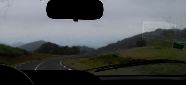 On the way to the mountain peaks by car, view from the passenger compartment, the landscape is blurred, the asphalt road turns to the right.