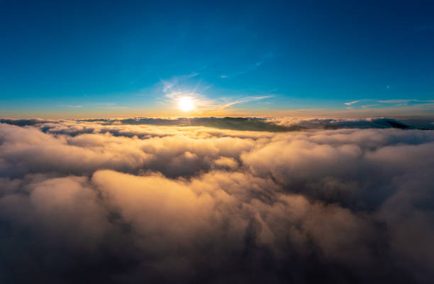 istock Sun shining brightly above white fluffy clouds at sunrise 1365901003