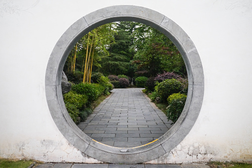 View through traditional Chinese circle gate into a lush garden