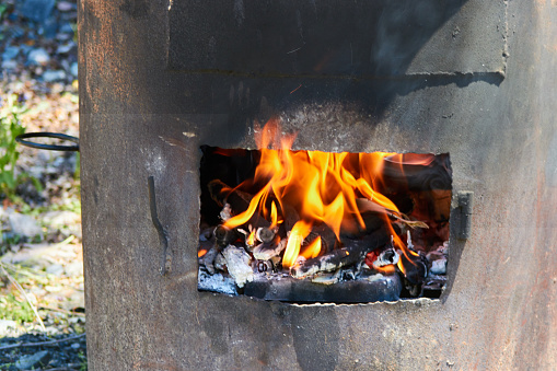 fire burning in a furnace made of rusty steel pipe for cooking outdoors