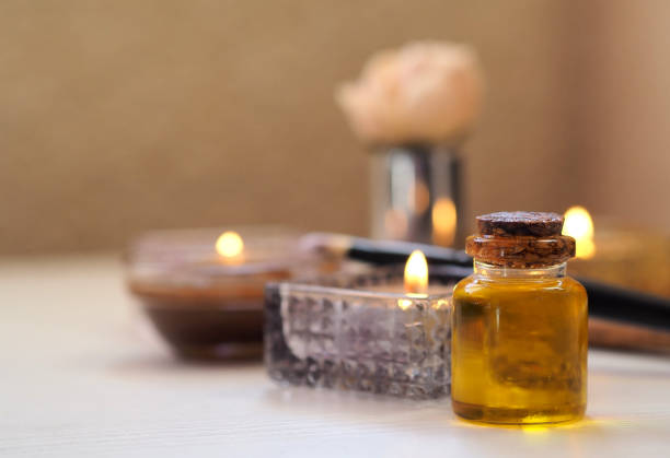 Close-up of a bottle of massage oil against the background of burning candles. Spa salon concept