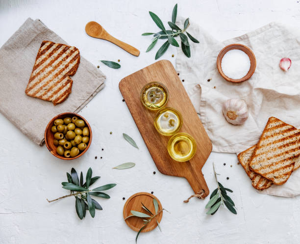 Flat lay green olives and olive oil. Top view composition with bread, olive branches stock photo