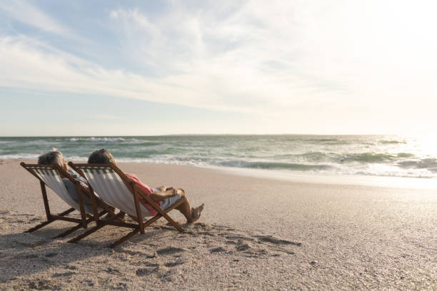 istock Biracial senior man and woman relaxing while sitting on folding chairs at beach 1365904685
