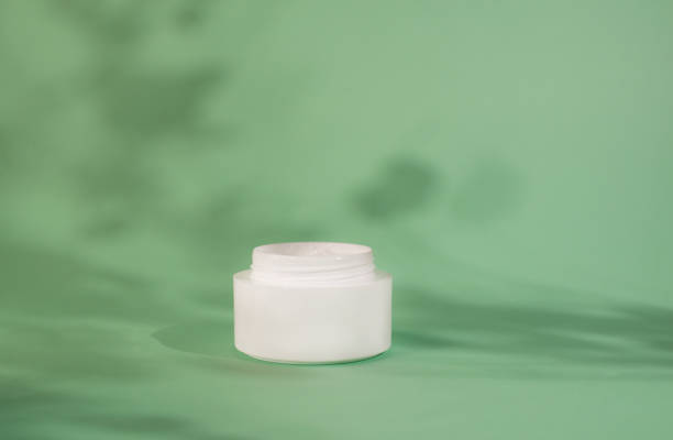 istock White moisturizer cream, shadow play on white background. Cream container mockup on mint background. Blank Cosmetics jar, packaging design. Skincare and body care concept. 1365905085