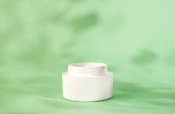 istock White moisturizer cream, shadow play on white background. Cream container mockup on mint background. Blank Cosmetics jar, packaging design. Skincare and body care concept. 1365905086