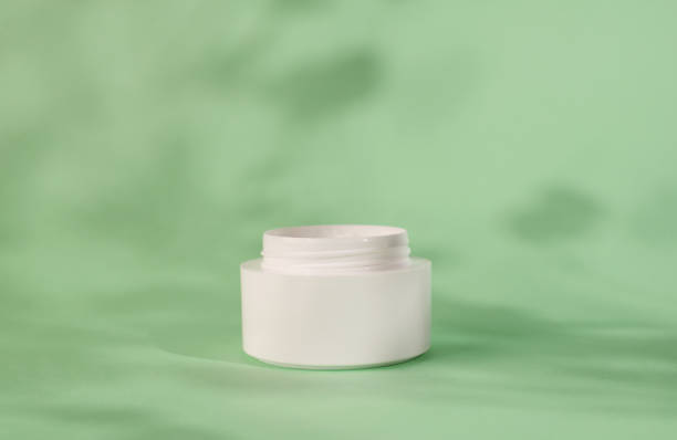 istock White moisturizer cream, shadow play on white background. Cream container mockup on mint background. Blank Cosmetics jar, packaging design. Skincare and body care concept. 1365905170