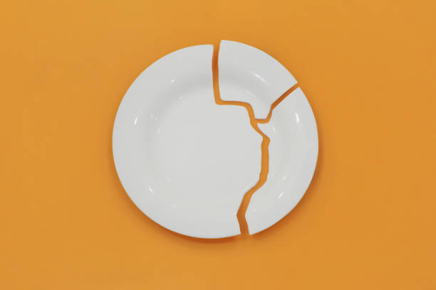 Top view on broken circle white plate on yellow background. The plate broke into three pieces.