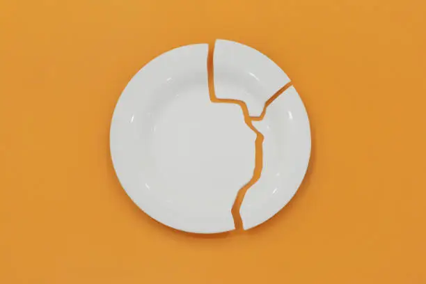 Top view on broken circle white plate on yellow background. The plate broke into three pieces. Concept photo.