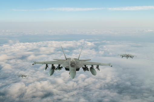 F-18 Jet fighters flying over clouds.