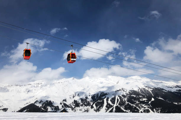 istock Two red gondolas lifting people to mountain peak for skiing 1365906517