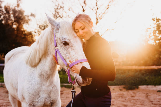 istock Deep friendship between a blond young girl and her white mare in a rustic stable outdoors in Majorca 1365906689