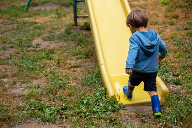 Little boy having fun on a slide in a rainy day