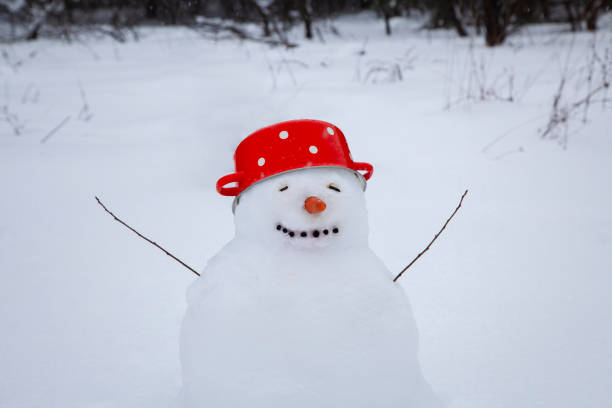 istock Funny snowman in a red soup pot with white dots instead of a hat 1365909820