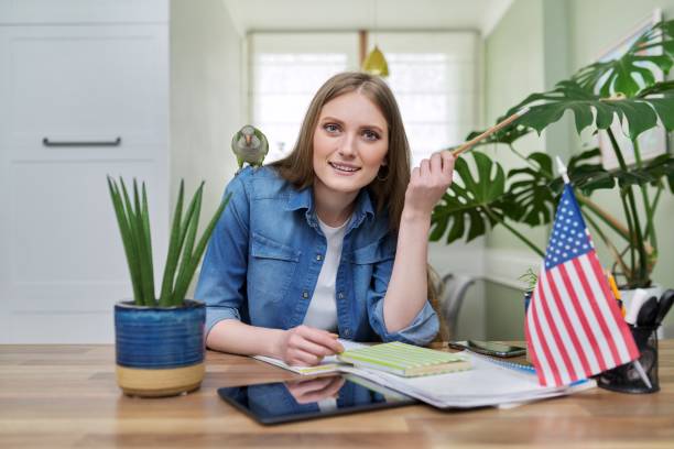 istock Young female student looking at the camera, USA flag on the table. 1365912524