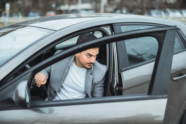 istock Handsome young man entering his car while standing outdoors 1365917866