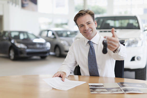 Car salesman handing keys over desk  car salesperson photos stock pictures, royalty-free photos & images