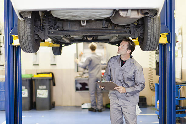 Mechanic examining underside of car  repair garage stock pictures, royalty-free photos & images