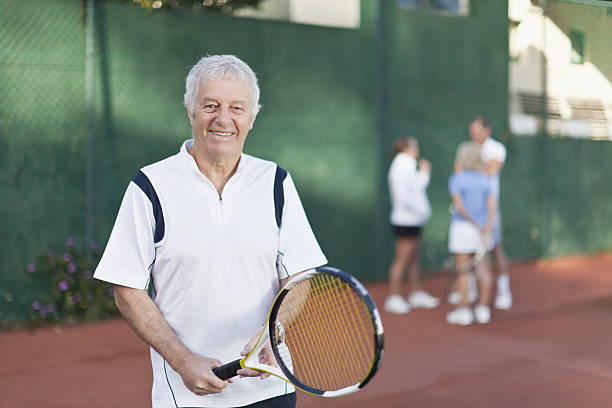 älterer mann hält tennis schläger am hof - tennis active seniors healthy lifestyle senior men stock-fotos und bilder