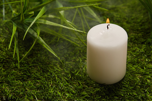 White paraffin candle on a green lawn
