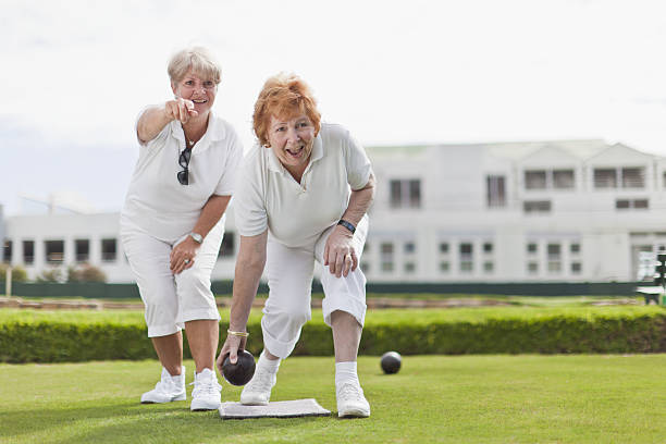 femmes plus âgées jouant bowling sur gazon - anticipation smiling touching image technique photos et images de collection