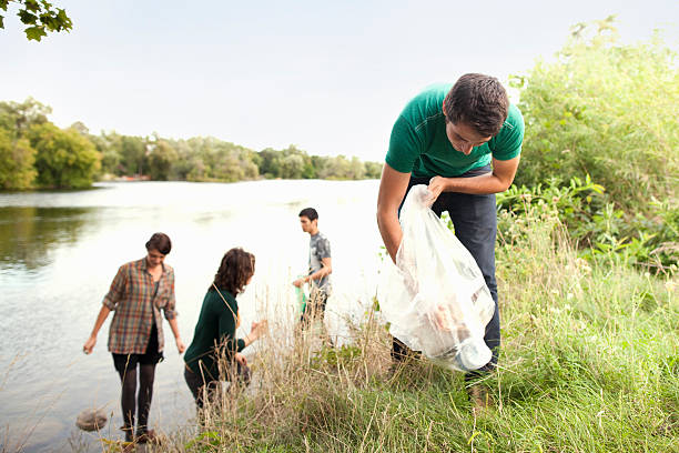 menschen, die abholung abfall in park - green garbage bag stock-fotos und bilder