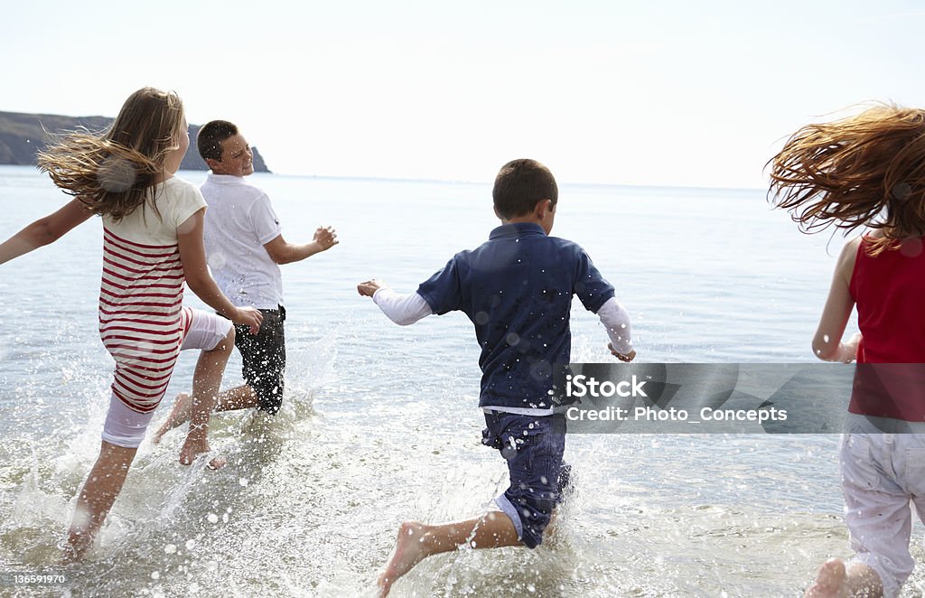 Enfants courir dans les vagues sur la plage - Photo de Cornouailles libre de droits