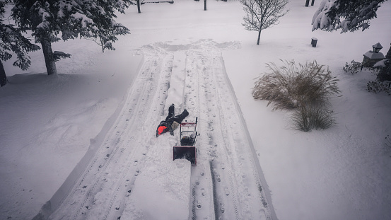 Man using snowblower in deep snow.Man slips on a snowy road.