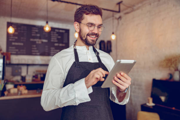 istock Cheerful male barista using tablet computer in cafe 1365920031