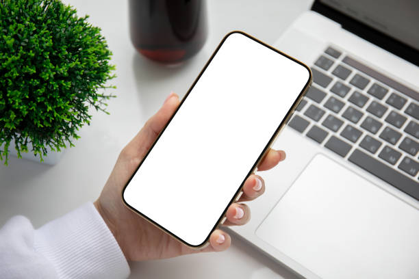 istock female hand holding phone with isolated screen over laptop 1365921073