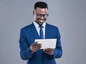 Cropped shot of a handsome young businessman using a tablet in studio against a grey background