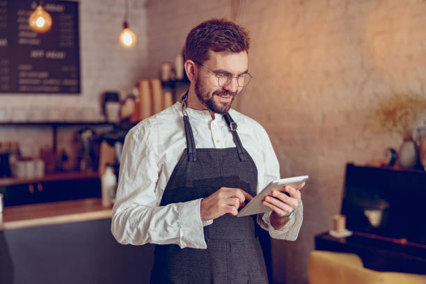 istock Cheerful male barista using tablet computer in cafe 1365921952