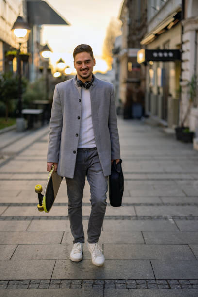istock Stylish bearded man with skate walking in city 1365924848