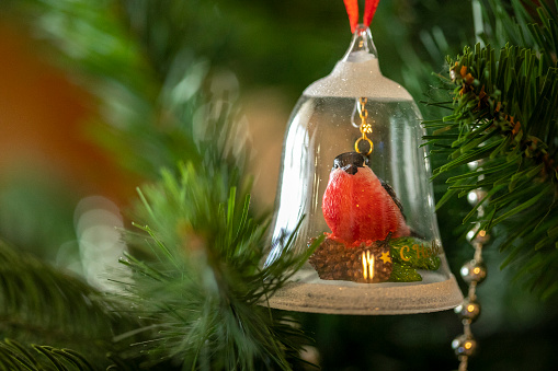 Closeup of toy snowbird hanging on a decorated Christmas tree under the glass bell