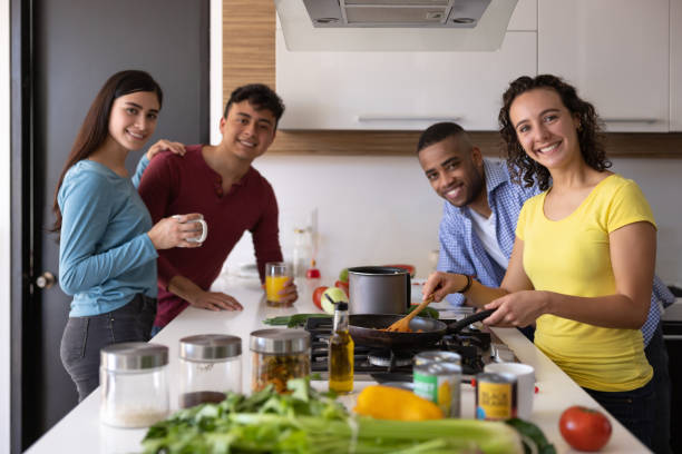 istock Happy group of flat mates cooking dinner together at home 1365930894