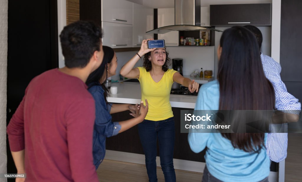Happy friends playing heads up at home Happy group of friends playing heads up at home using a cell phone - entertainment concepts Party Game Stock Photo