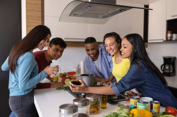 istock Happy flat mates cooking together while looking at social media 1365930918