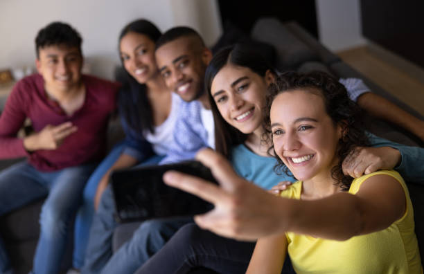 istock Happy group of flat mates taking a selfie at home 1365930938