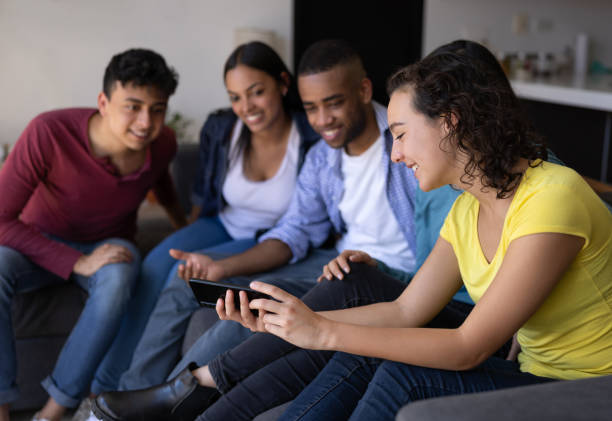 istock Group of flat mates watching a video on a cell phone while relaxing at home 1365930954