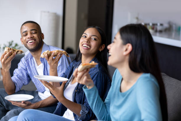 istock Happy group of flat mates having fun eating pizza at home 1365931050