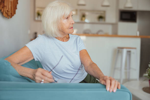 istock Pensioner female sitting on sofa at home 1365933221
