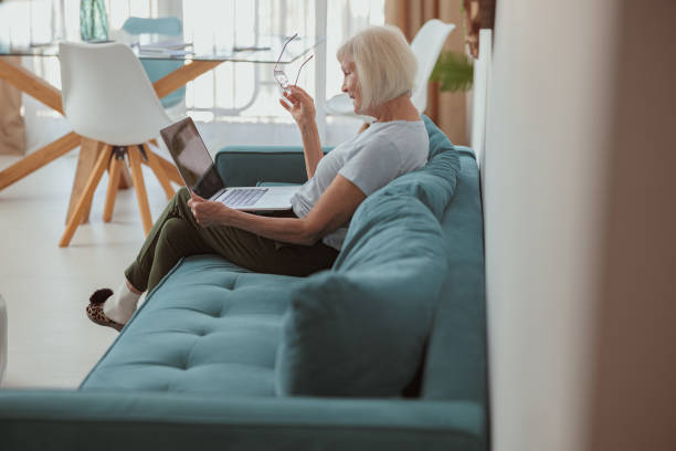 istock Senior woman using laptop while sitting at home 1365933254
